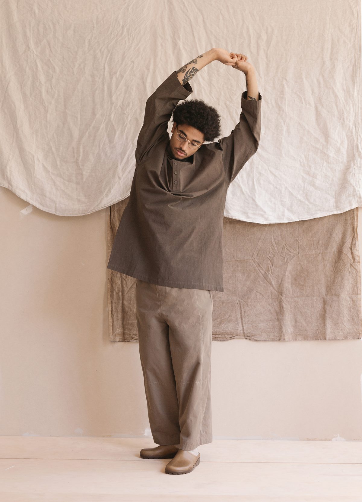 Satta SS25: overshirt and wide trousers, arms stretched overhead