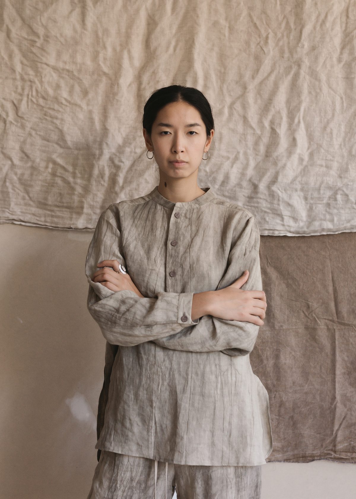 Satta SS25 womenswear: grey linen shirt, arms crossed