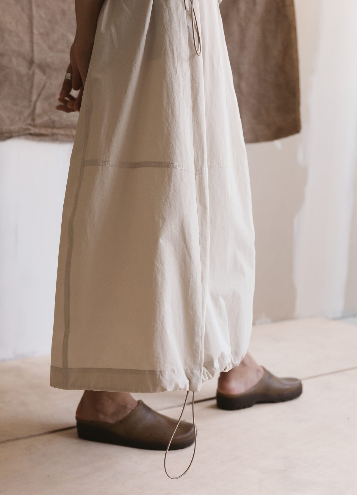 Drawcord hem of a long ecru skirt