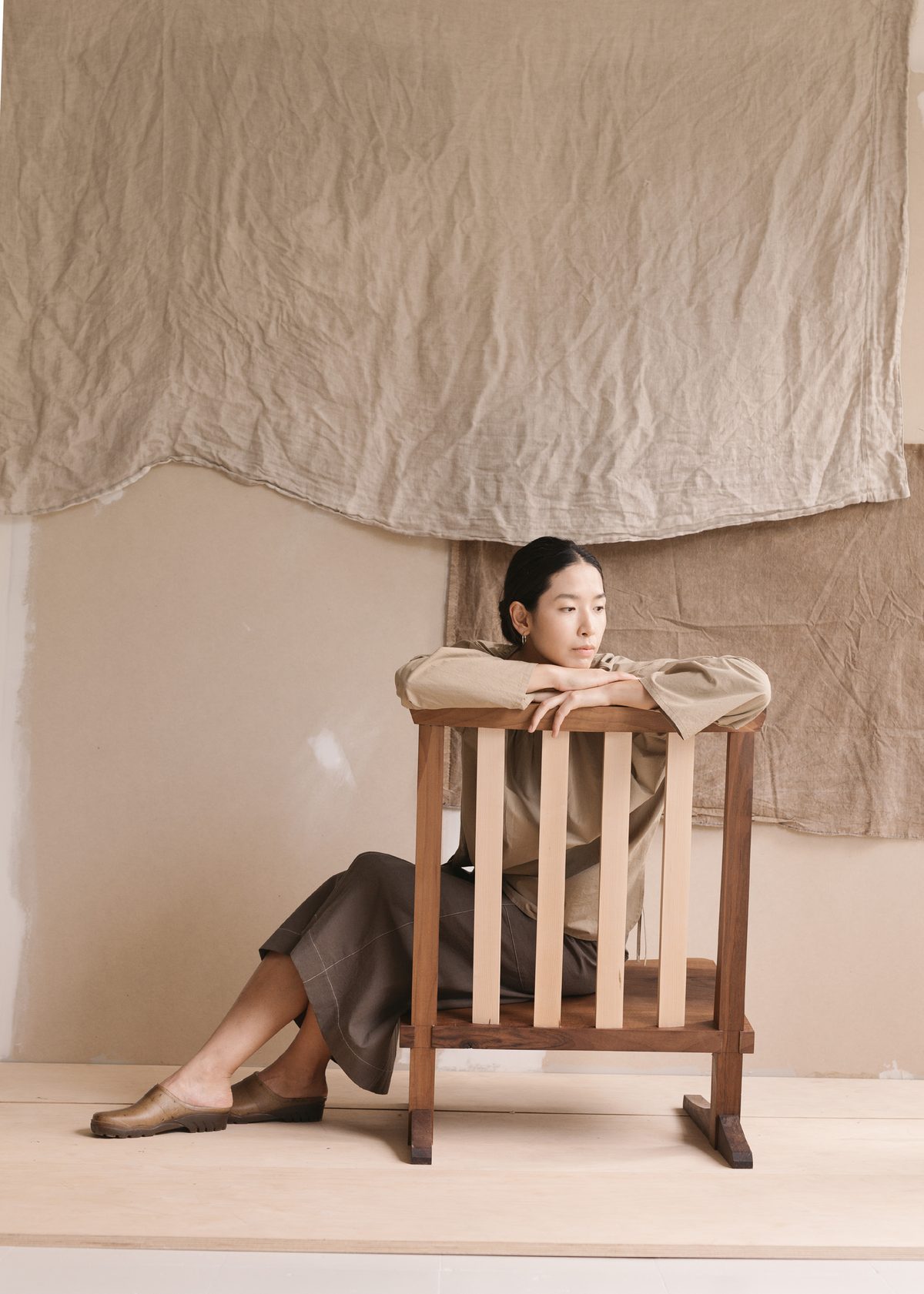 Seated backwards on a wooden chair in a long skirt